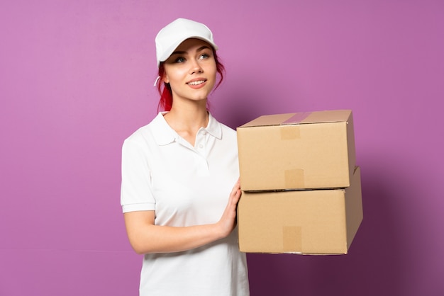 Teenager delivery girl on purple wall thinking an idea while looking up