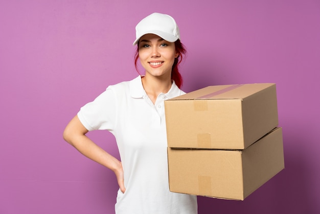 Teenager delivery woman isolated on purple wall keeping the arms crossed in frontal position