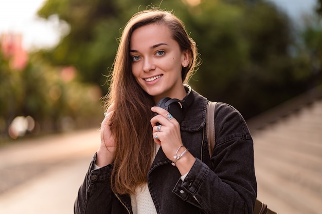 Teenager enjoys and listens to music in black wireless headphones while walking around the city