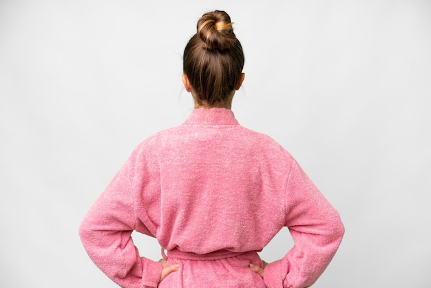 Teenager girl in a bathrobe over isolated white background in back position