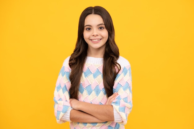 Teenager girl crossed arms isolated on yellow background Studio portrait of child with mock up copy space