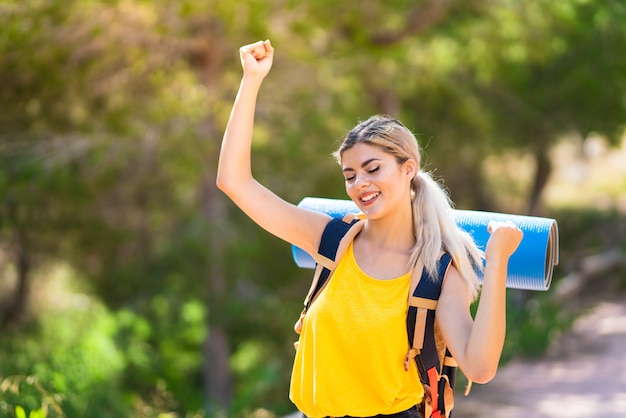 Teenager girl hiking at outdoors celebrating a victory in winner position