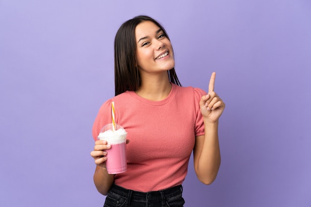 Teenager girl holding a strawberry milkshake pointing up a great idea