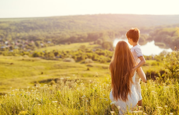 Teenager girl hugging little brother in field