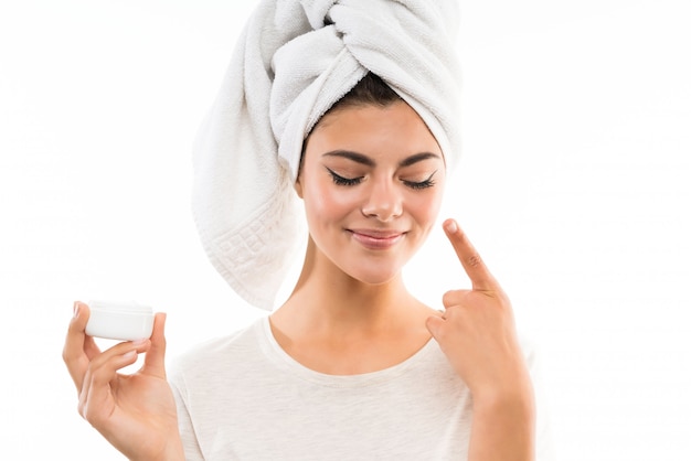 Teenager girl over isolated white background with moisturizer