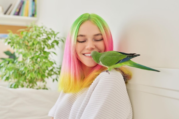 Teenager girl kissing a parrot Closeup face of beautiful young woman and green quaker parrot love of the owner and pet bird