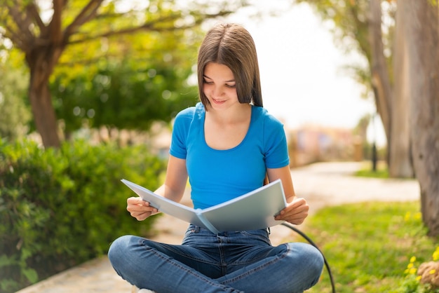 Teenager girl at outdoors holding a notebook