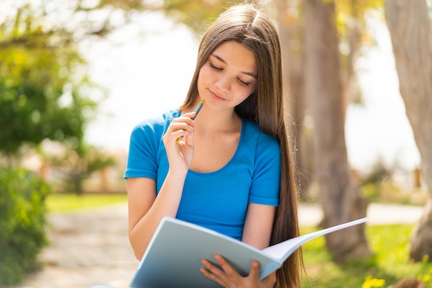 Teenager girl at outdoors holding a notebook