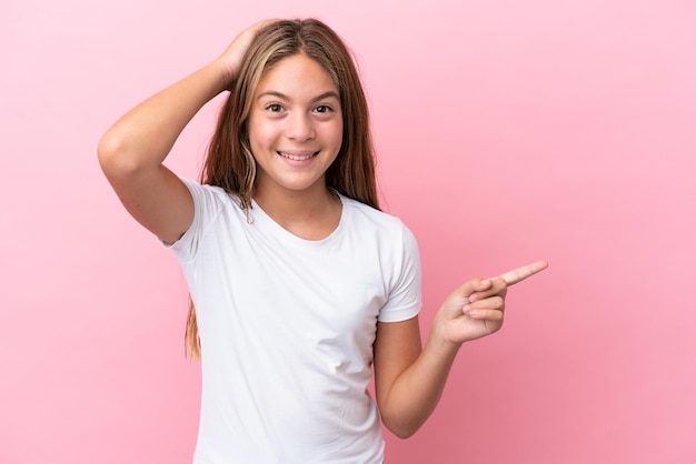 Teenager girl playing basketball over grey wall looking up while smiling