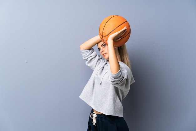 Photo teenager girl playing basketball over grey wall 