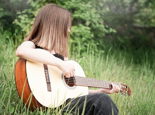 Teenager girl playing guitar in the park