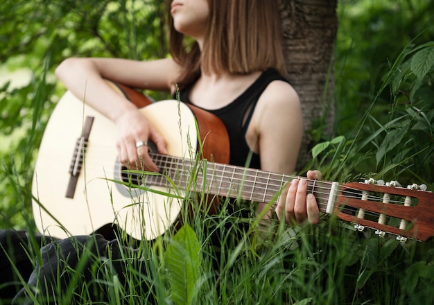 Teenager girl playing guitar in the park