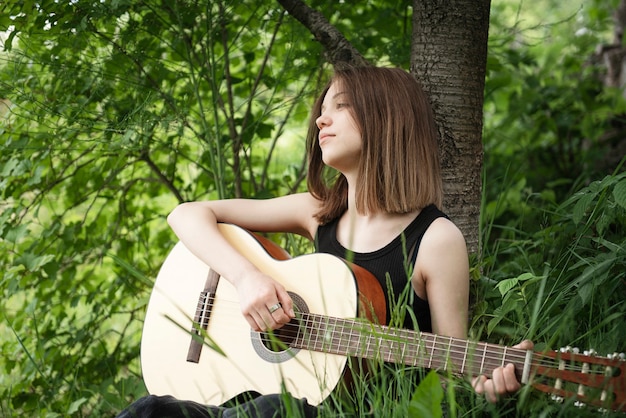 Teenager girl playing guitar in the park