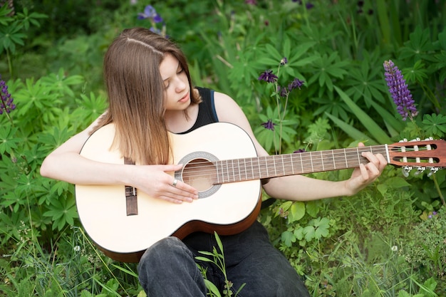 Teenager girl playing guitar in the park