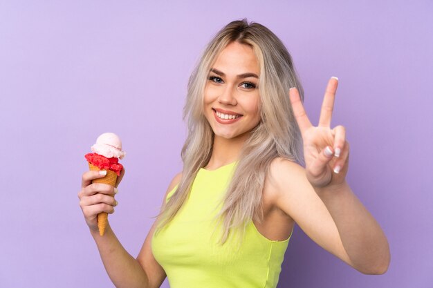 Teenager girl over purple smiling and showing victory sign