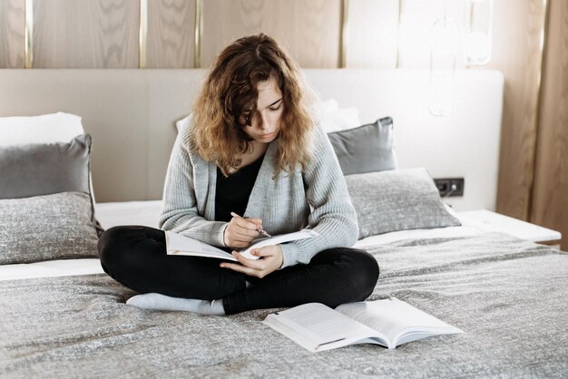 Teenager girl studying on the bed at home. Student doing homework