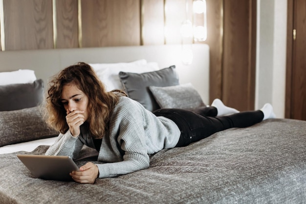 Teenager girl watching video on tablet lying on the bed