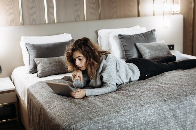 Teenager girl watching video on tablet lying on the bed