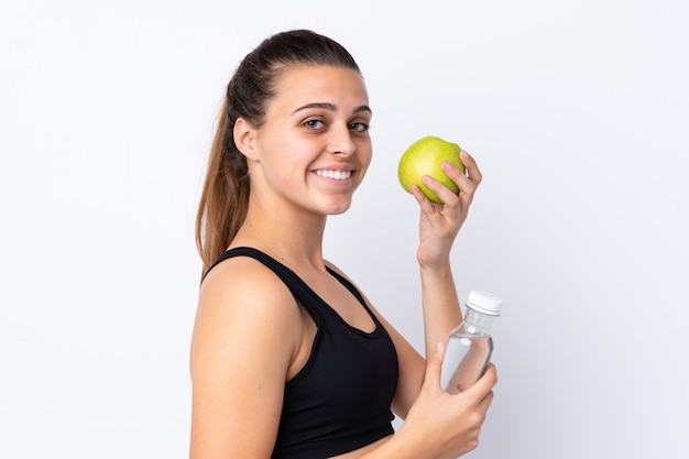 Teenager girl with an apple and a bottle of water over isolated wall