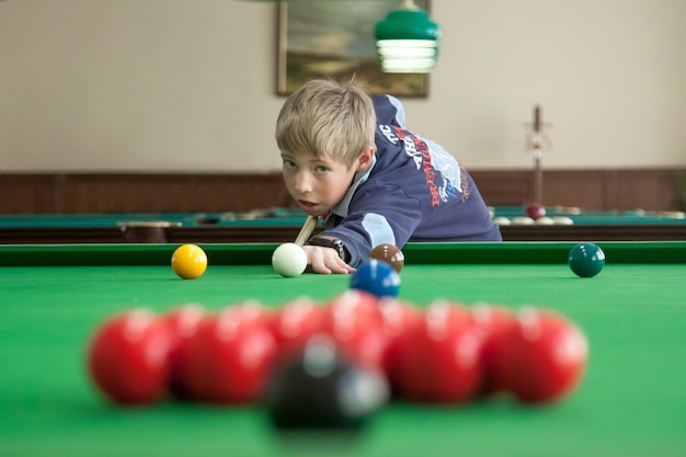 Teenager is playing snooker Red balls are in the foreground