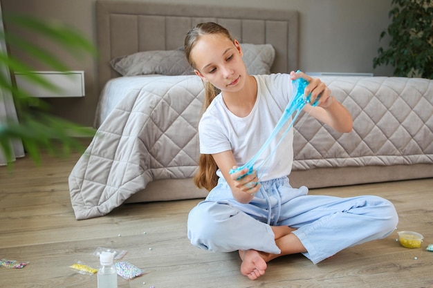 A teenager is playing with a blue slime Concept of girl made homemade goo