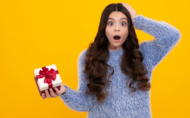 Teenager kid with present box Teen girl giving birthday gift Present greeting and gifting concept Shocked amazed face surprised emotions of young teenager girl