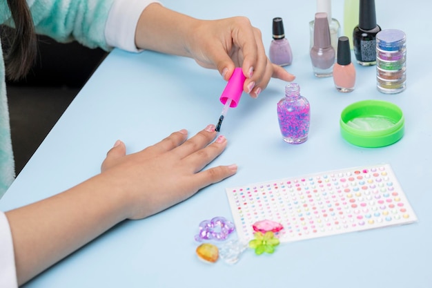 Teenager painting her nails at home with varnish products