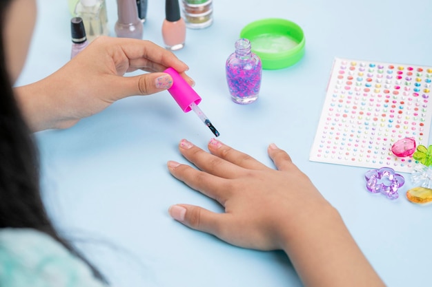 Teenager painting her nails at home with varnish products