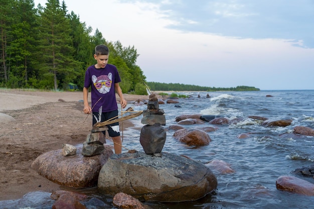 A teenager puts stones in pyramids on the shore of a lake