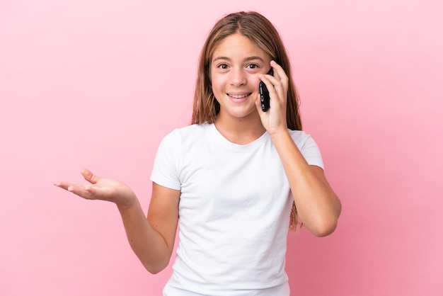 Teenager redhead girl holding an orange over isolated yellow background