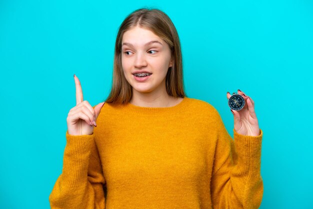 Teenager Russian girl holding compass isolated on blue background intending to realizes the solution while lifting a finger up