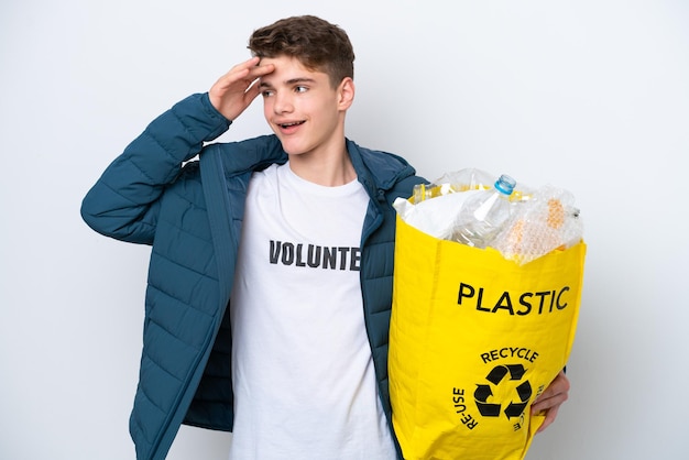 Teenager Russian holding a bag full of plastic bottles to recycle on white background smiling a lot