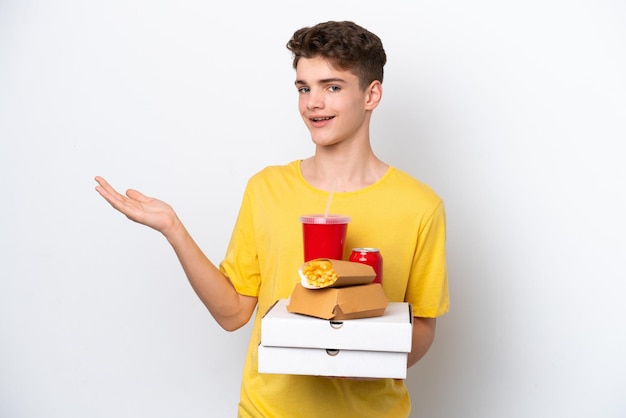 Teenager Russian man holding fast food isolated on white background extending hands to the side for inviting to come