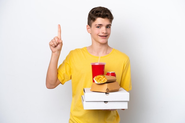 Teenager Russian man holding fast food isolated on white background showing and lifting a finger in sign of the best