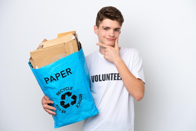 Teenager Russian man holding a recycling bag full of paper to recycle isolated on white background thinking