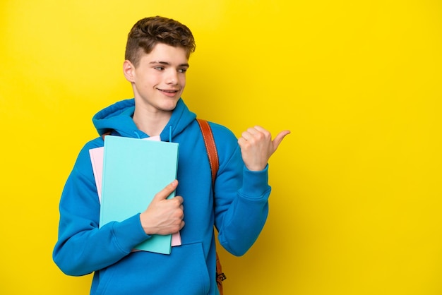 Teenager Russian student man isolated on yellow background pointing to the side to present a product