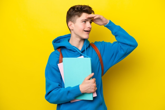 Teenager Russian student man isolated on yellow background smiling a lot