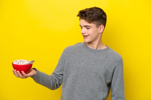 Teenager Russian woman holding a yellow background with happy expression