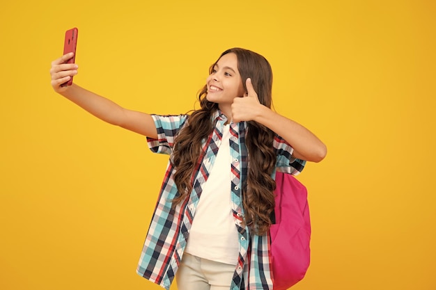 Teenager school student girl with mobile phone on isolated background