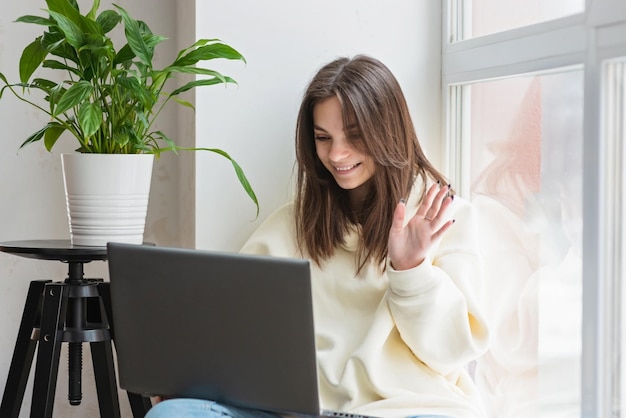 Teenager schoolgirl pupil distance learning online at remote virtual class with teacher by video conference call watching webinar zoom meeting lesson on laptope at home Soft selective focus