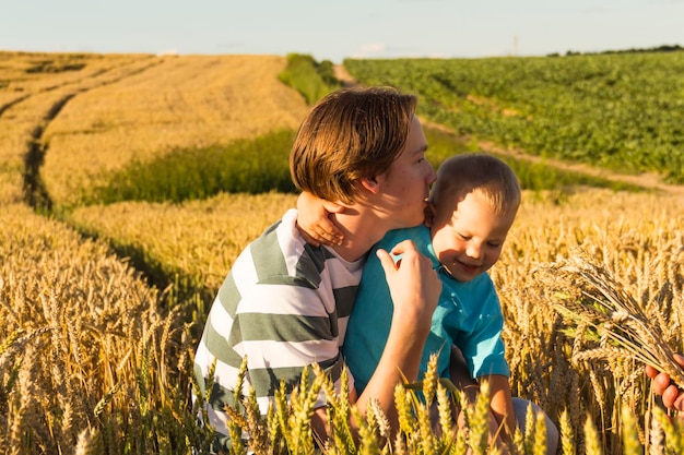 A teenager and a small child are walking carefree and fun in a field with wheat It's time to harvest The food crisis in the world