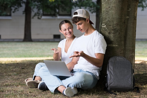 Teenager students working on laptop in a park