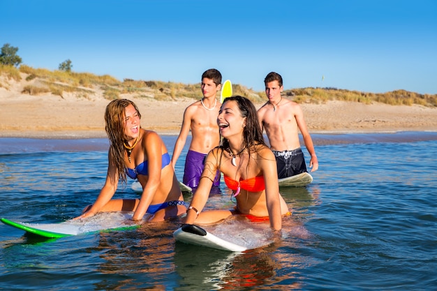 Teenager surfer boys and girls swimming ove surfboard