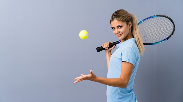 Teenager tennis player girl over grey wall