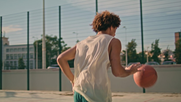 Teenager throwing ball basket back view modern sportsman playing urban game