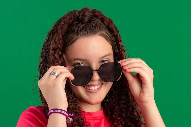 Teenager wearing glasses in fun poses in a studio photo with a green background ideal for cropping