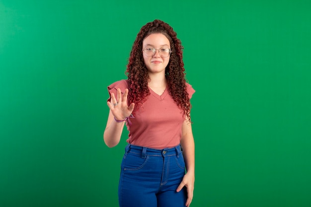 Teenager wearing glasses in fun poses in a studio photo with a green background ideal for cropping