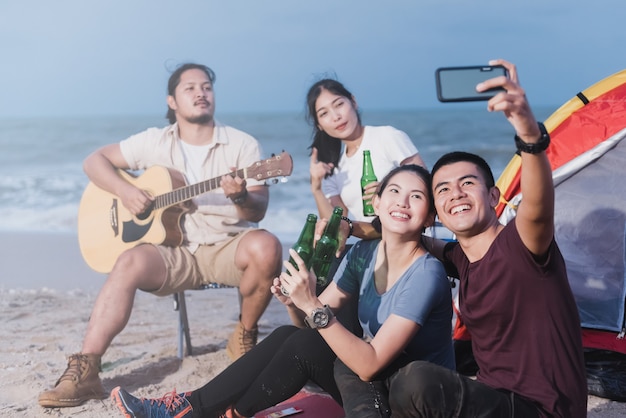 Teenagers in a camping, taking a selfie using a smartphone