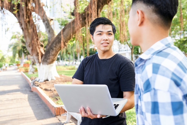 Teenagers using laptop outdoors