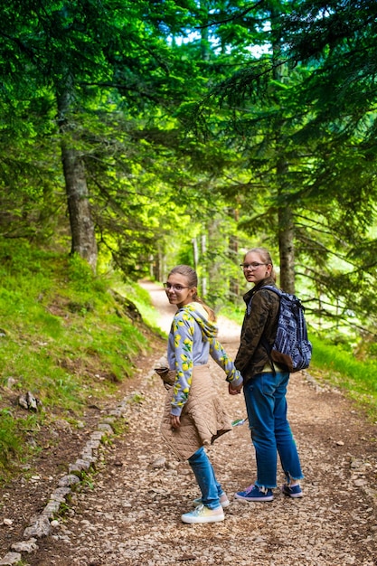 Teenagers with backpacks hiking in forest Summer vacation